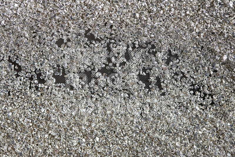 Silver shimmering fragments of glass scattered on a black background