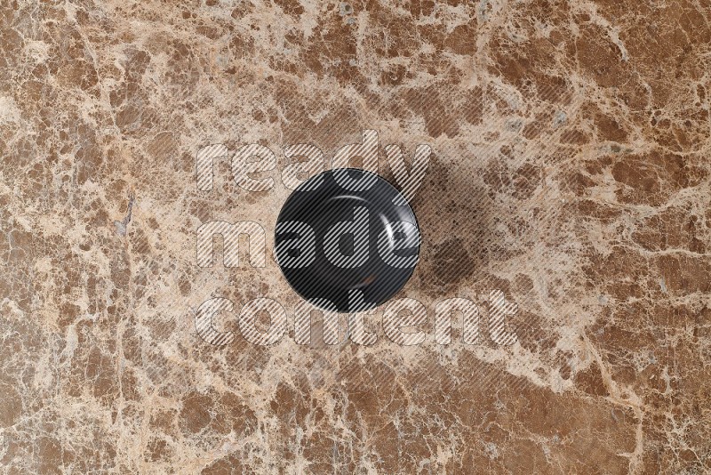 Top View Shot Of A Black Ceramic Bowl On beige Marble Flooring