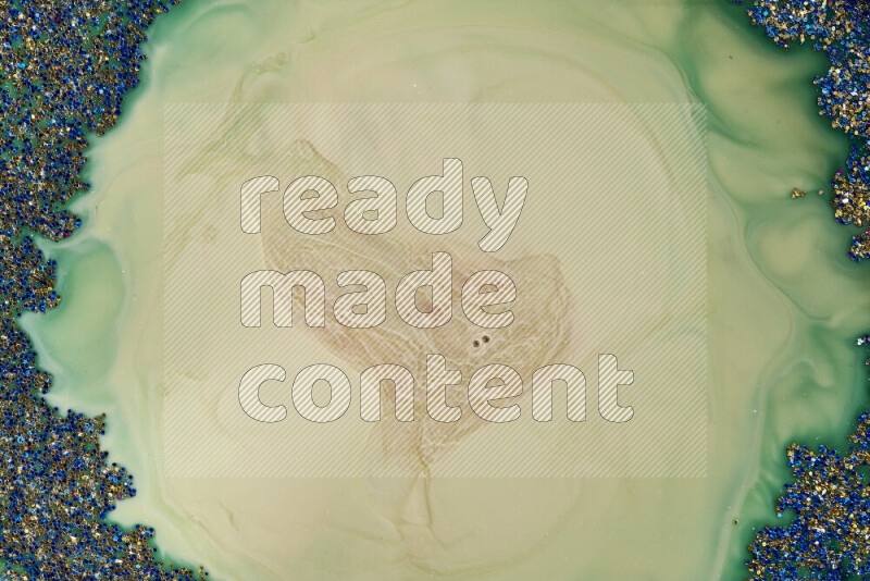 A close-up of sparkling blue glitter scattered on swirling blue and green background