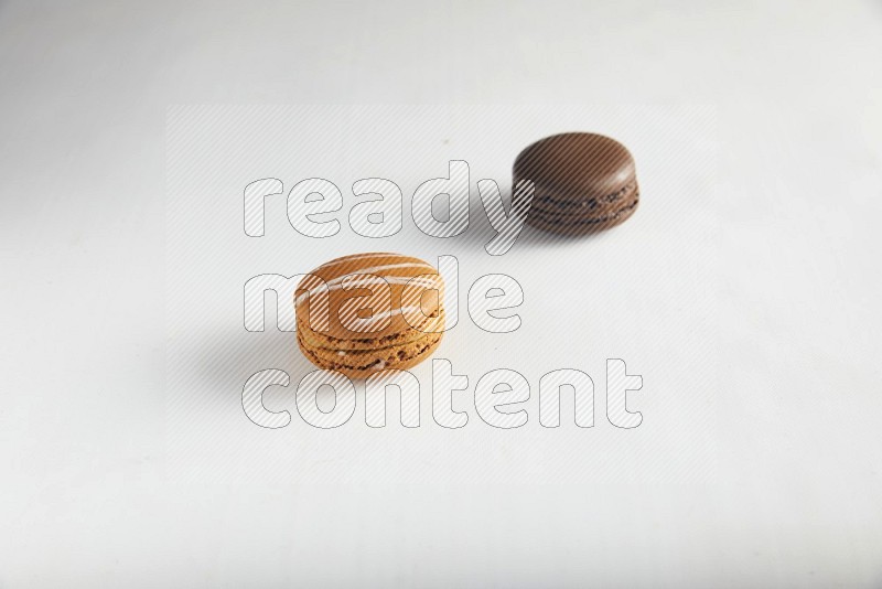 45º Shot of of two assorted Brown Irish Cream, and Brown Dark Chocolate macarons on white background