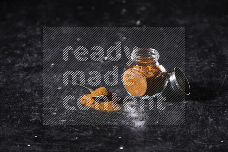 A glass jar full of ground paprika powder on black background