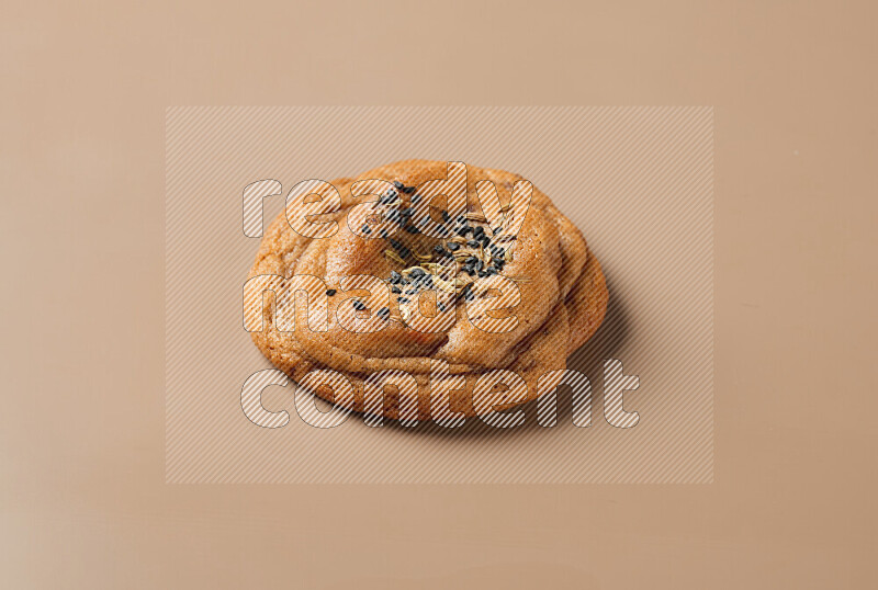 a whole Hasawi cookie with grains on a brown background