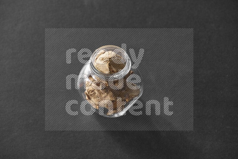 A glass spice jar full of ginger on black flooring