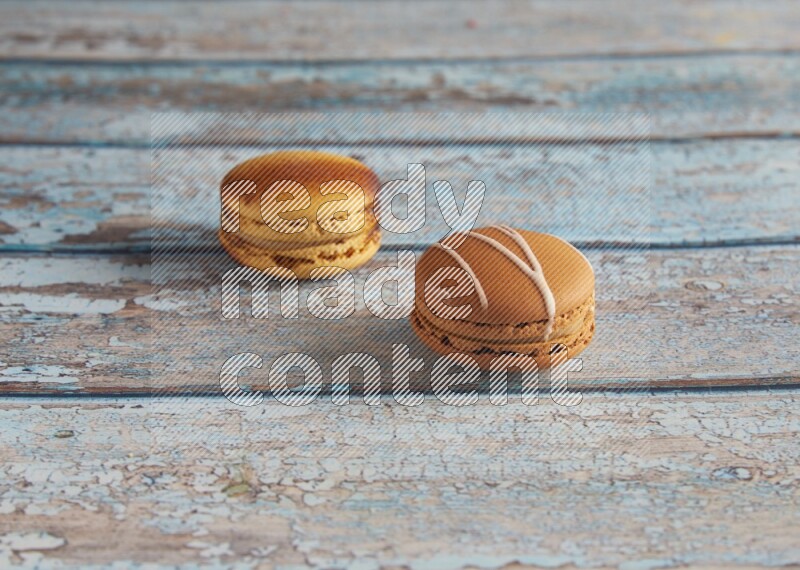 45º Shot of of two assorted Brown Irish Cream, and Yellow Crème Brulée macarons on light blue background