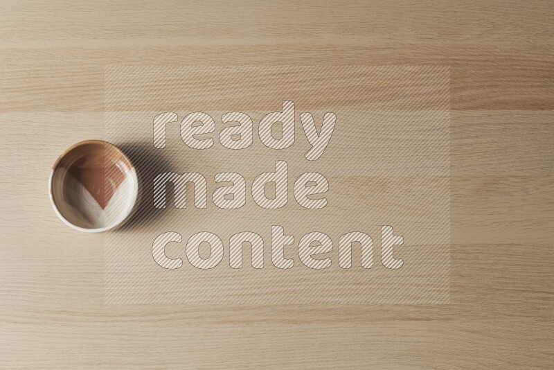 A multicolored pottery bowl on light wooden background