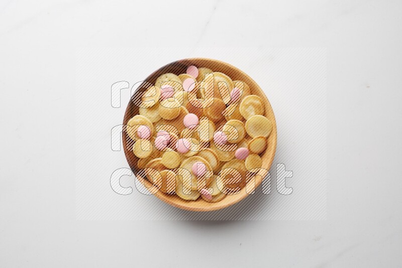 Top-view shot of pink chocolate chips cereal pancakes in a round bowl on white background
