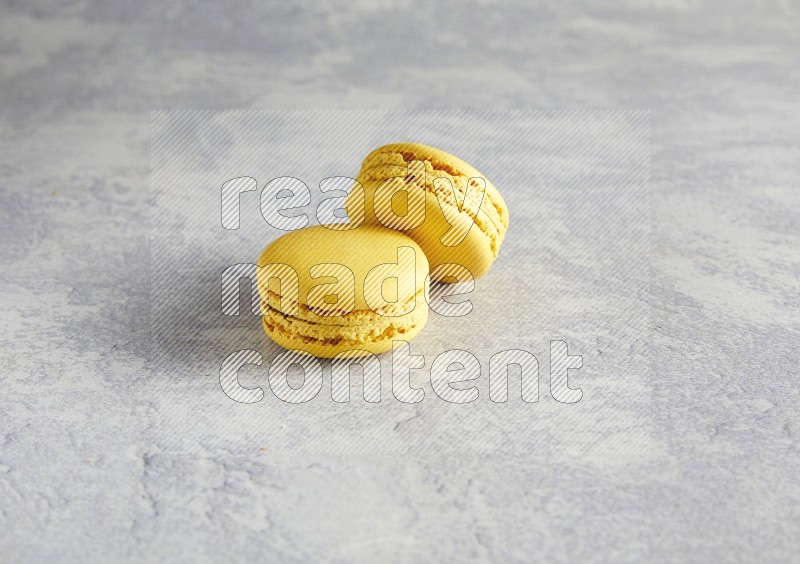 45º Shot of two Yellow Lemon macarons  on white  marble background