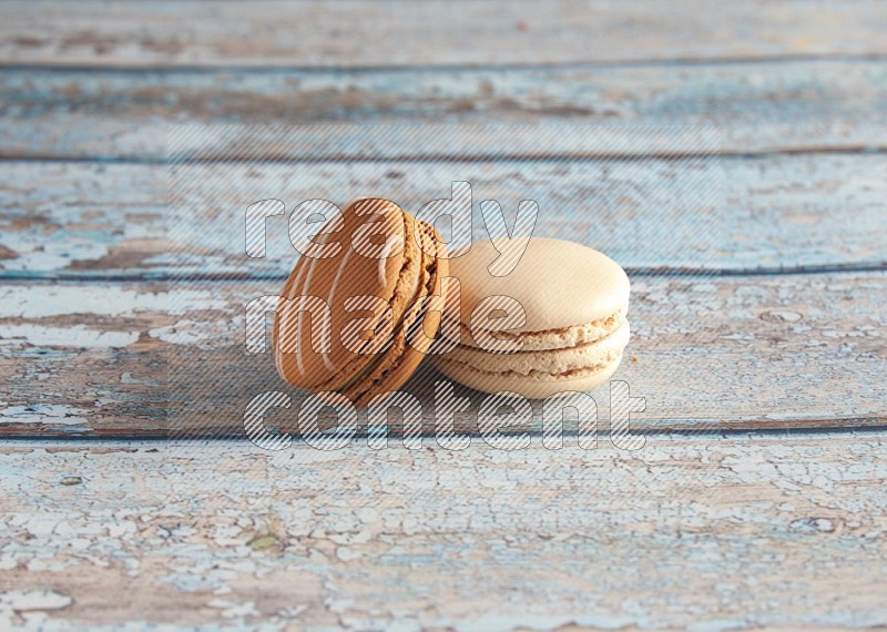 45º Shot of of two assorted Brown Irish Cream, and White Caramel fleur de sel macarons on light blue background