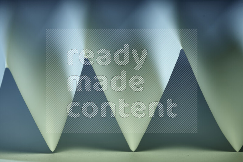 صورة مجردة مقربة تظهر طيات ورقية هندسية حادة بتدرجات اللون الأخضر والأزرق