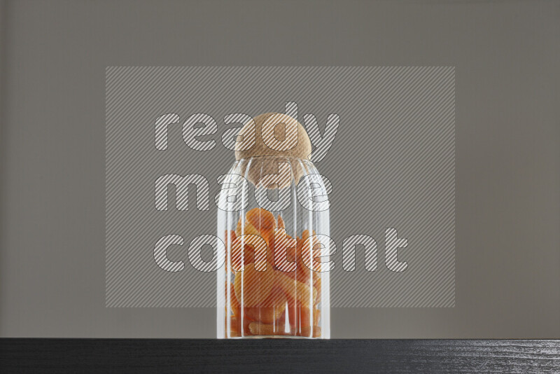 Dried apricots in a glass jar on black background