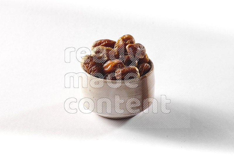 Dates in a beige pottery bowl on white background