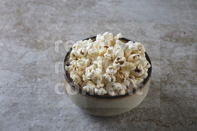 popcorn in multi-colored pottery bowl on a grey textured countertop