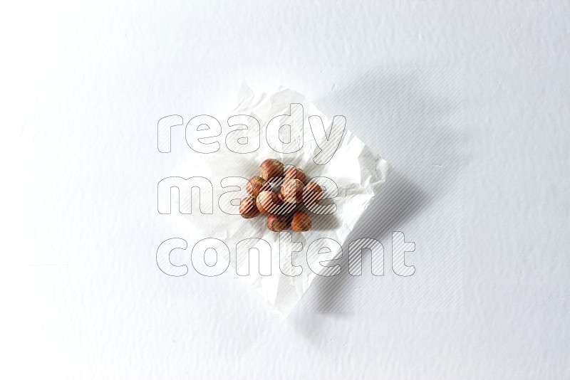 Hazelnuts on a crumpled piece of paper on a white background in different angles