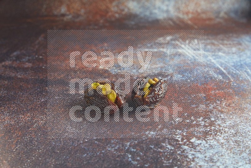 two pistachio stuffed madjoul dates on a rustic reddish background