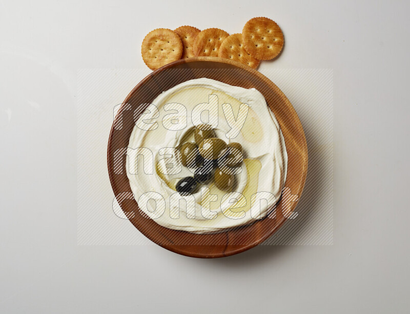 Lebnah garnished with whole olives in a wooden plate on a white background