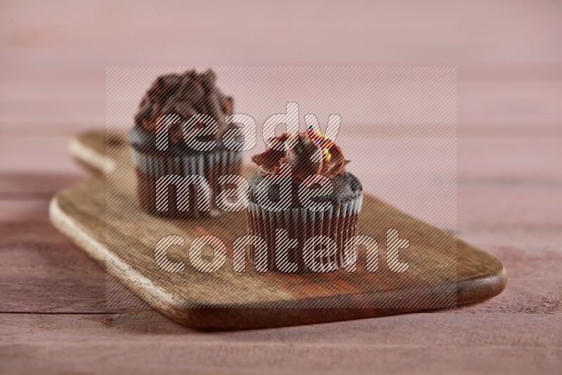Chocolate mini cupcake topped with chocolate cream on a wooden board