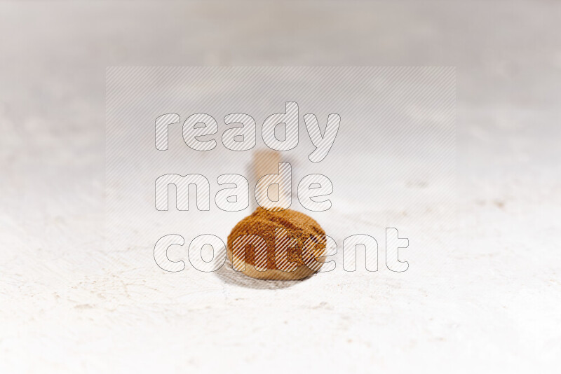 A wooden spoon full of ground paprika powder on white background