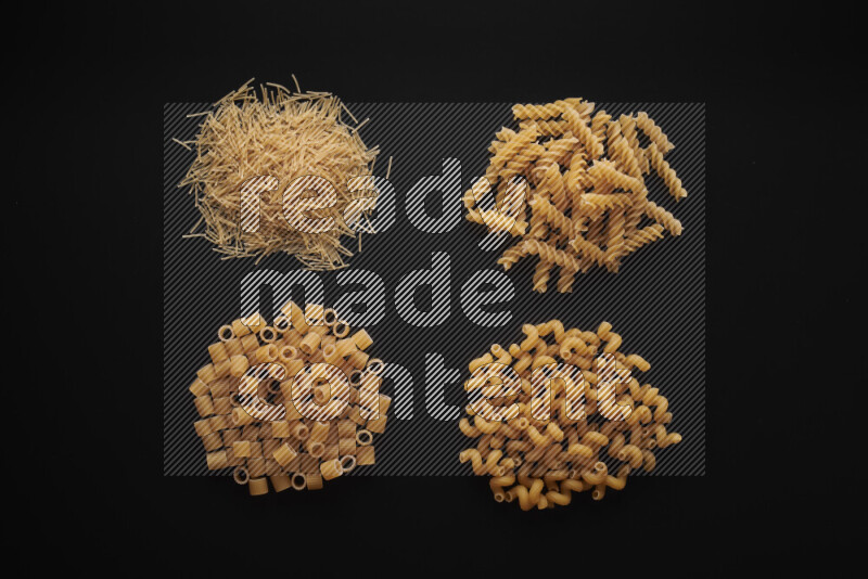 Different pasta types in bunches on black background