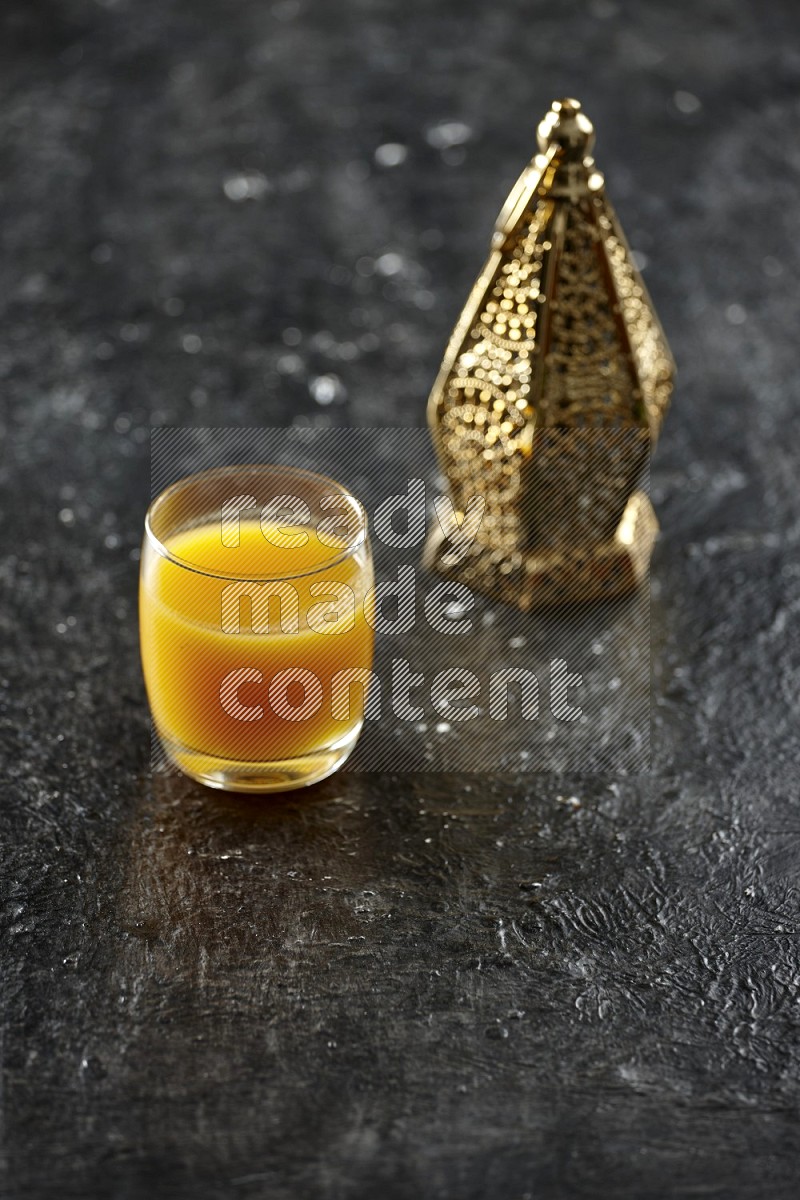 A golden lantern with different drinks, dates, nuts, prayer beads and quran on textured black background