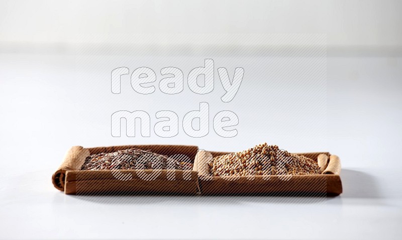 2 squares of cinnamon sticks full of mustard seeds and flaxseeds on white flooring