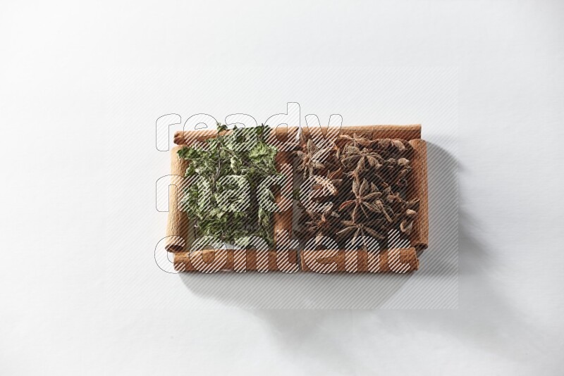 2 squares of cinnamon sticks full of star anise and dried mint leaves on white flooring