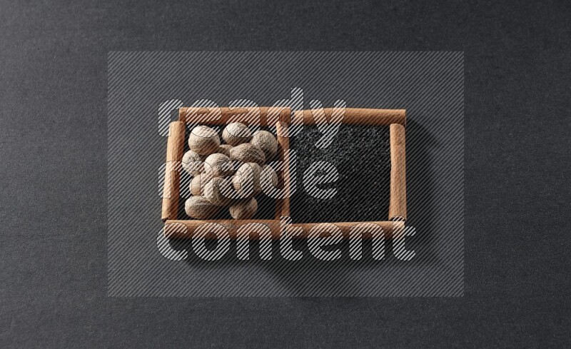 2 squares of cinnamon sticks full of black seeds and nutmeg on black flooring