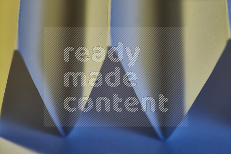 A close-up abstract image showing sharp geometric paper folds in blue gradients and warm tones