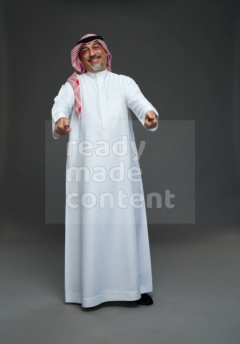 Saudi man with shomag Standing Interacting with the camera on gray background