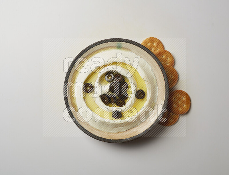 Lebnah garnished with sliced olives in a pottery plate on a white background