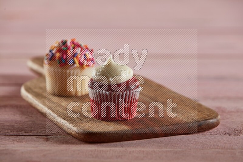 Red velvet mini cupcake topped with cream on a wooden board