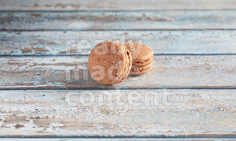 45º Shot of two Brown Hazelnuts macarons on light blue wooden background