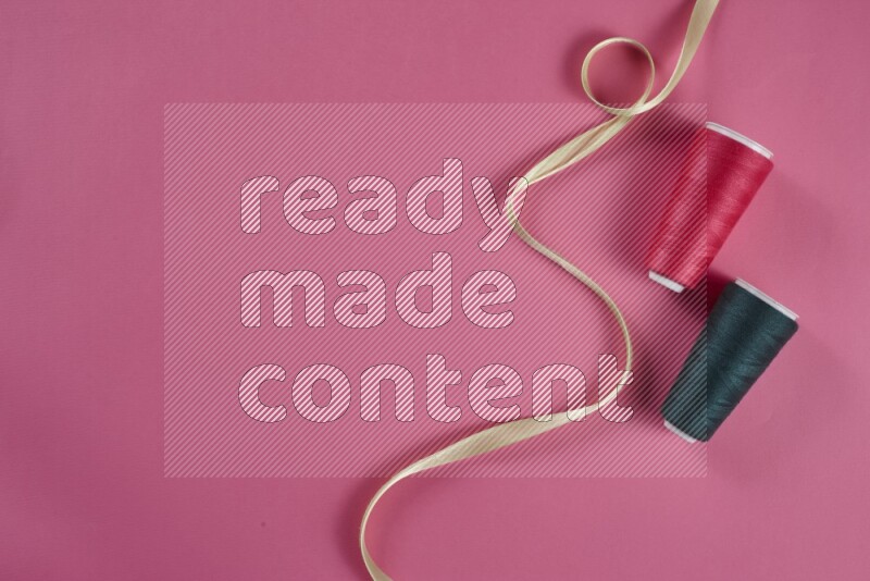 مجموعة من أدوات الخياطة والتفصيل خضراء وزهرية اللون على خلفية زهرية