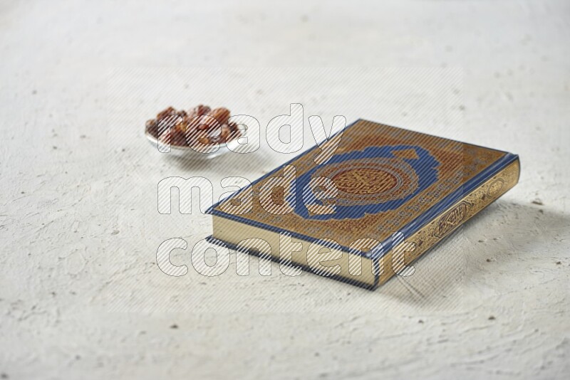 Quran with dates, prayer beads and different drinks all placed on textured white background
