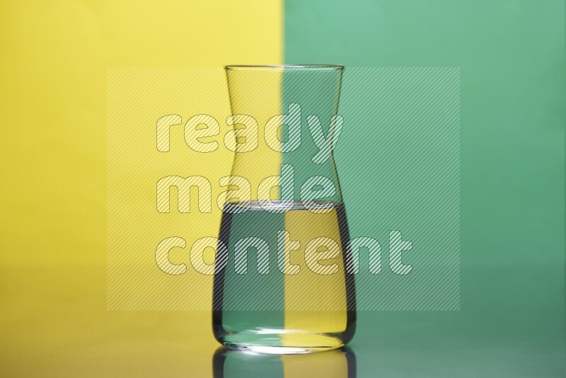 The image features a clear glassware filled with water, set against yellow and green background