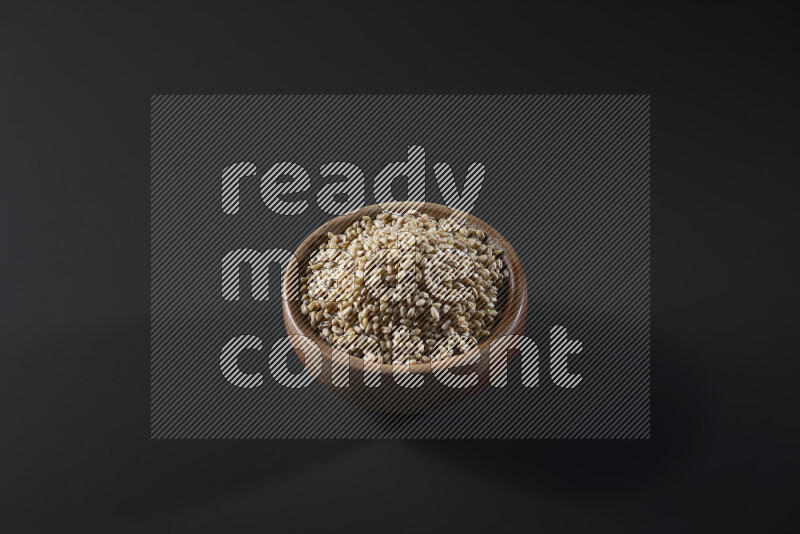 Hulled wheat in a wooden bowl on grey background