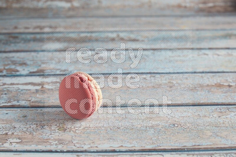 45º Shot of Pink Litchi Raspberry macaron on light blue wooden background