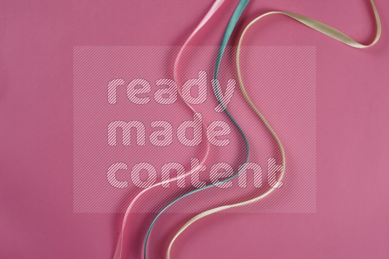 مجموعة من أدوات الخياطة والتفصيل خضراء وزهرية اللون على خلفية زهرية