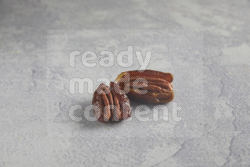 TWO pecan stuffed dates on alight grey background