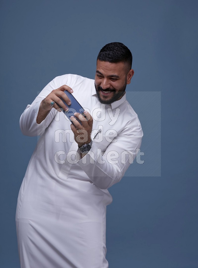 رجل سعودي يرتدي ثوب ابيض ويلعب في جواله