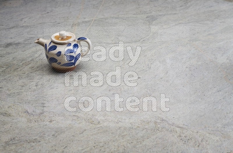 A Pottery Teapot On Grey Marble Flooring