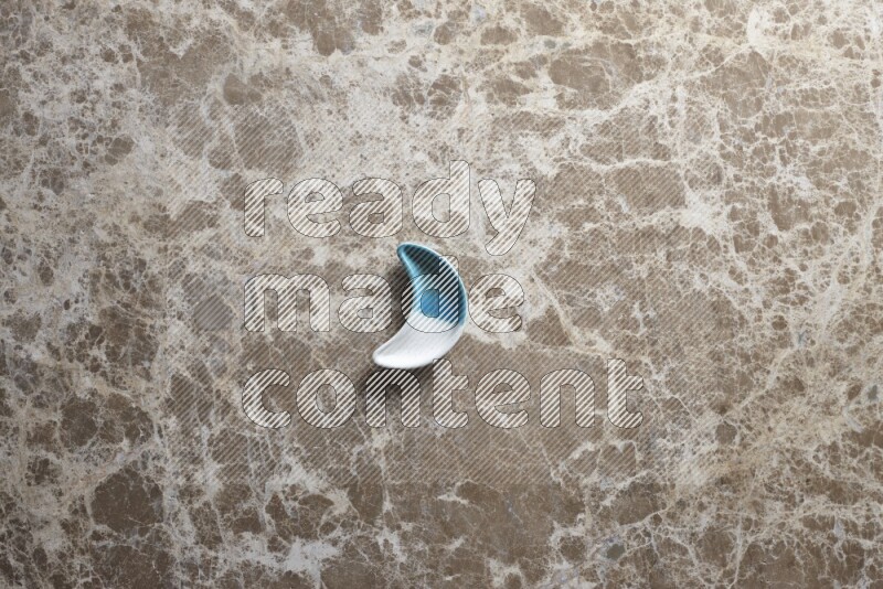 A pottery crescent plate on beige marble background
