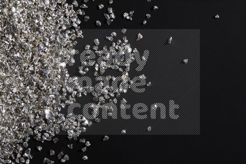 قطع زجاجية فضية لامعة متناثرة على خلفية سوداء