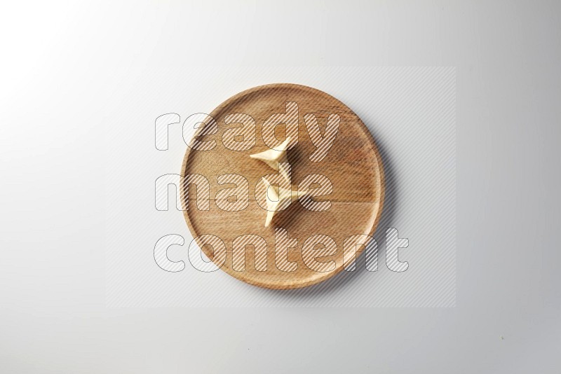 Two Sambosas on a wooden round plate on a white background