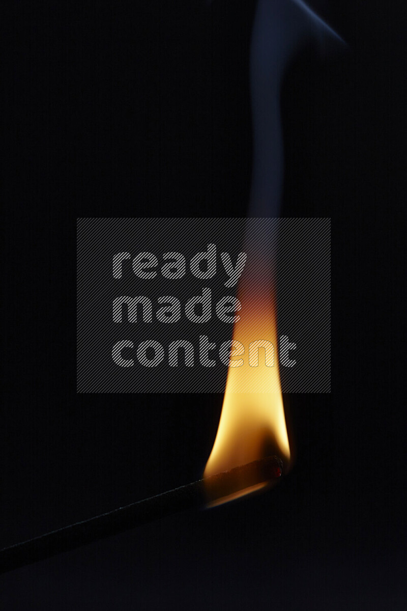 A burning incense stick isolated on dark backdrop