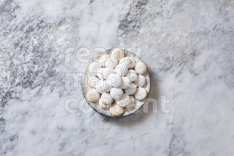 كحك في صحن فخار أسود على خلفية رخام رمادي