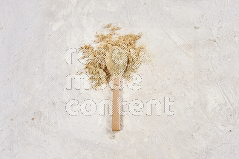 A wooden spoon full of ground ginger powder on white background