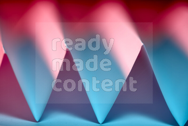 A close-up abstract image showing sharp geometric paper folds in blue and red gradients