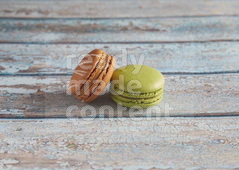 45º Shot of of two assorted Brown Irish Cream, and Green Pistachio macarons  on light blue background