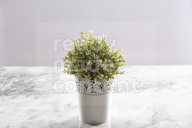 Artificial plant in white decorative pot on grey marble background