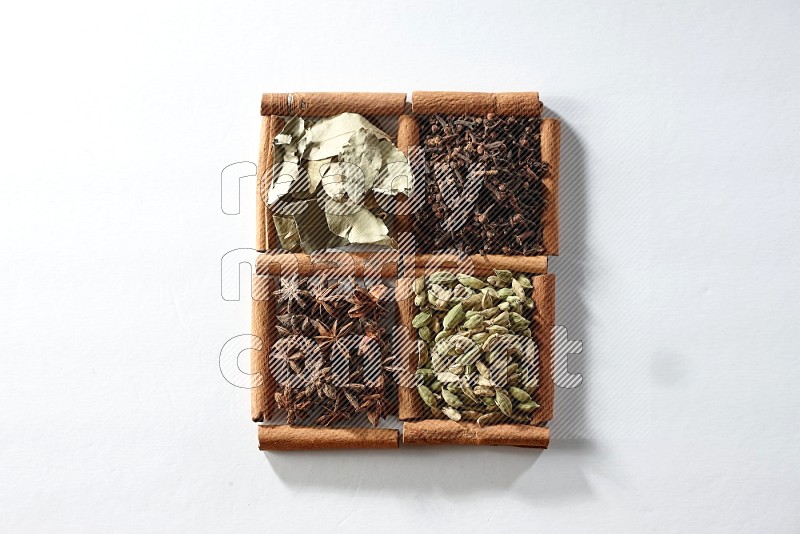 4 squares of cinnamon sticks full of cardamom, star anise, cloves and bay laurel leaves on white flooring